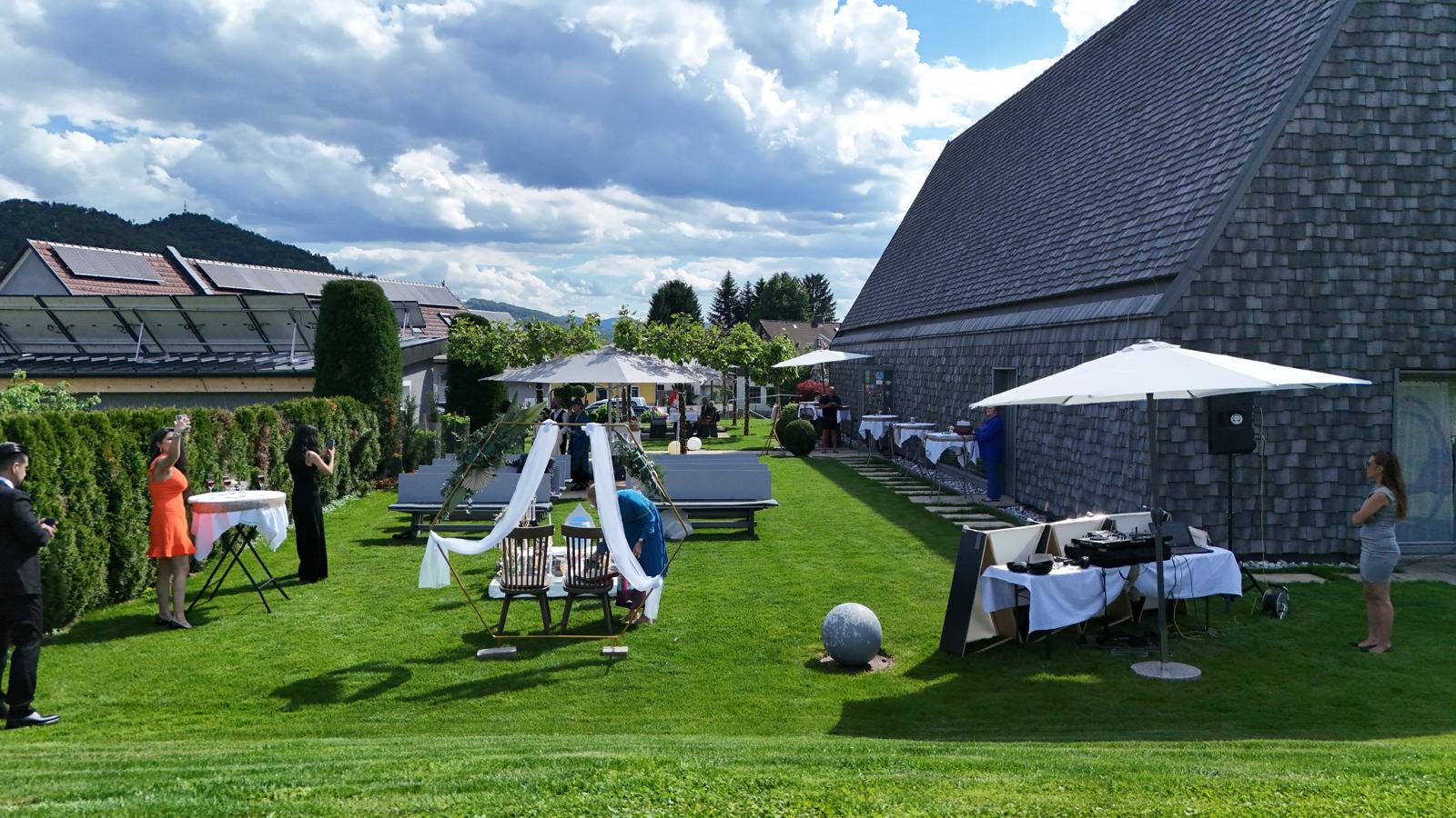 Gartenbereich des Weinguts Wutte bei einer Feier mit dekorierten Sitzbereichen, DJ-Pult und Gästen.