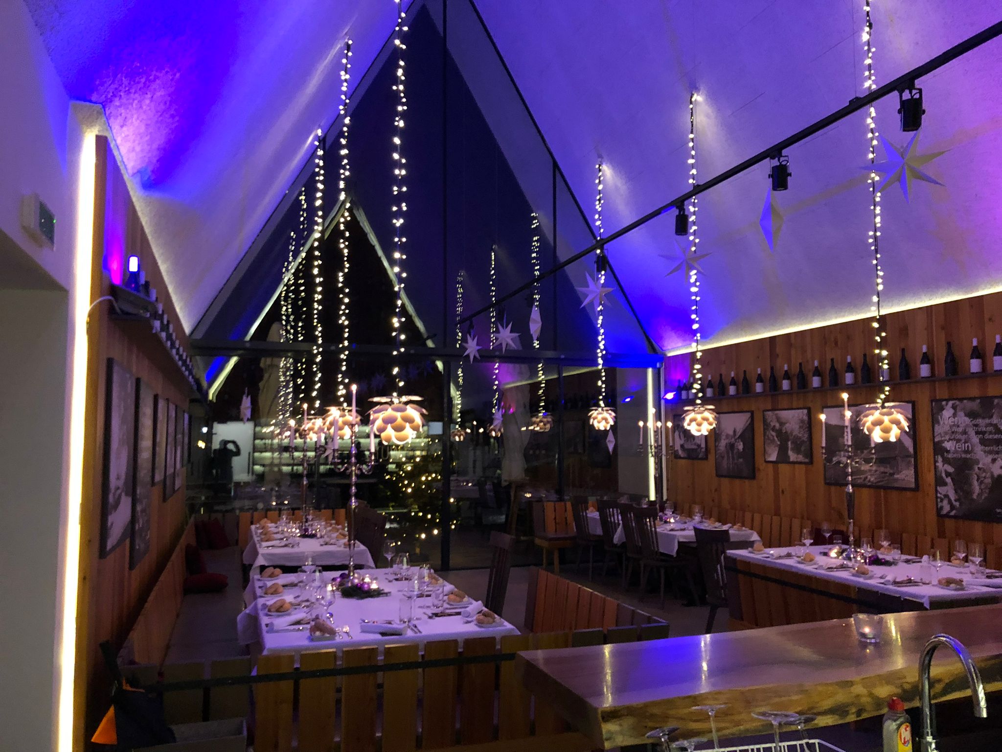 Innenraum des Buschenschanks Wutte abends, mit Lichterketten, gedeckten Tischen und stimmungsvoller Beleuchtung.